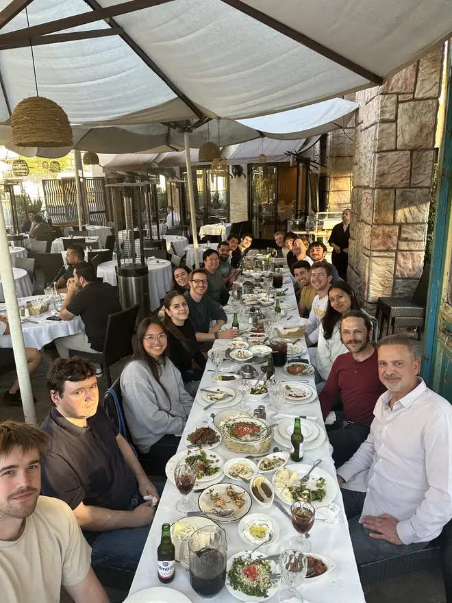 The team sharing a meal down a long restaurant table