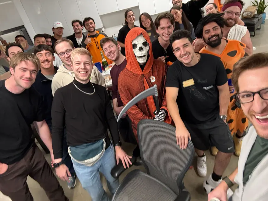 The team crowded together in Halloween costumes at the office