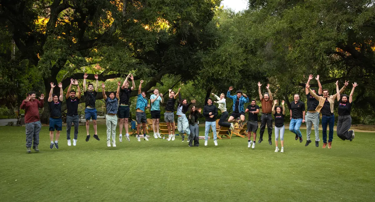 The Pirros team leaping in the air together on a lawn at a company offsite