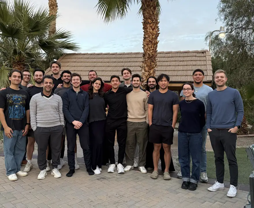 The team gathered outdoors under palm trees at an offsite