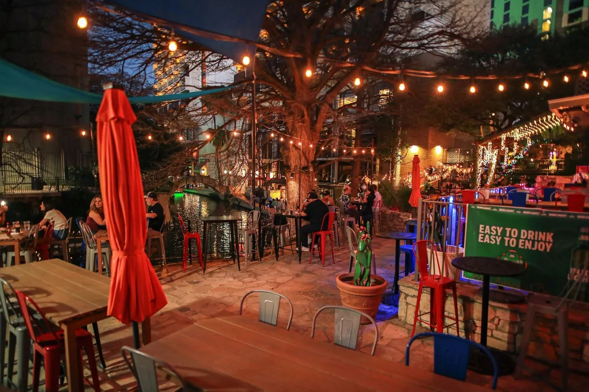 Texas River Bar patio under string lights beside the San Antonio River at night